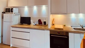Eine moderne Küche mit weißen Schränken, einer Mikrowelle, einem Geschirrspüler und einer Holz Arbeitsplatte.