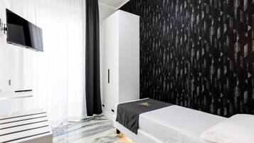 A modern bedroom with a bed, a flat-screen TV mounted on the wall, and a patterned wallpaper.