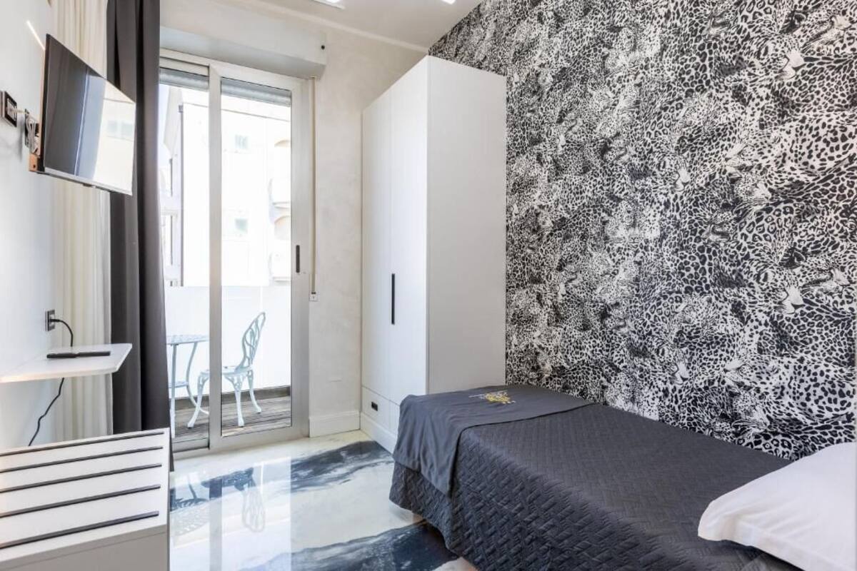 A bedroom with a bed, a wardrobe, a desk, and a chair.