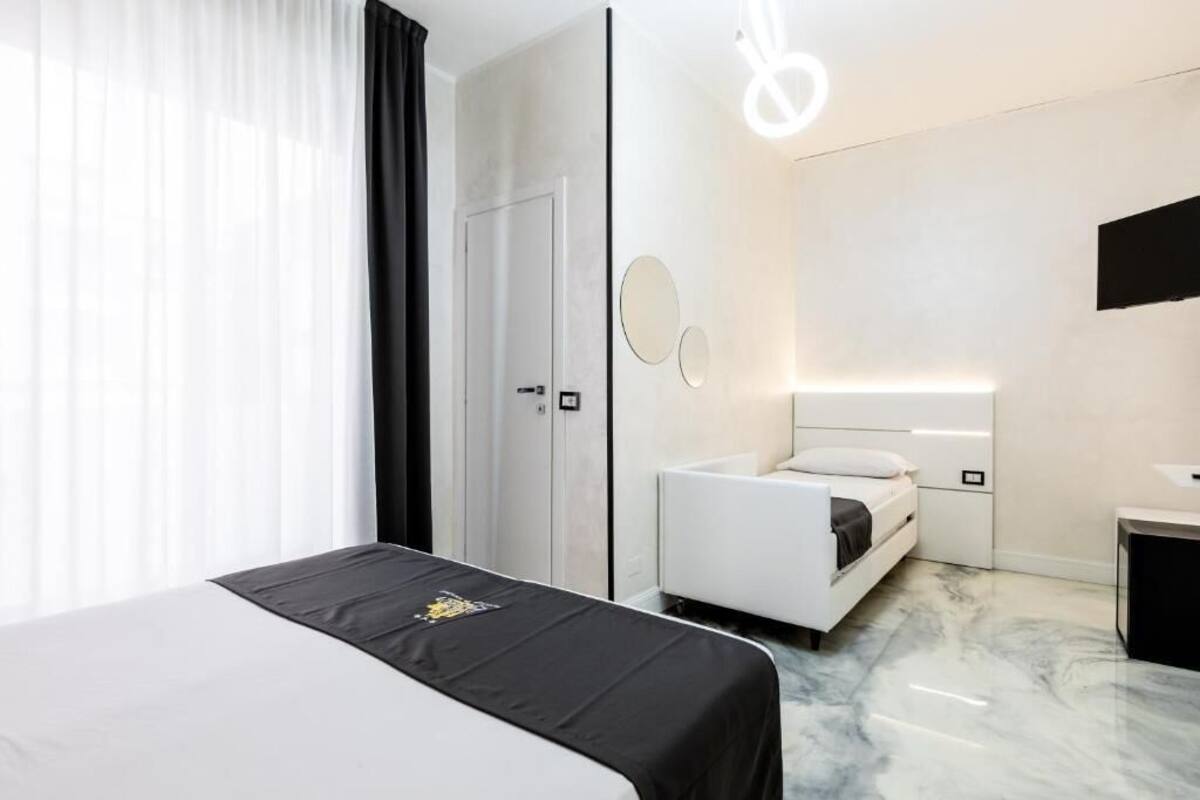 A modern hotel room with a large bed, a bedside table, a mirror, and a nightstand.