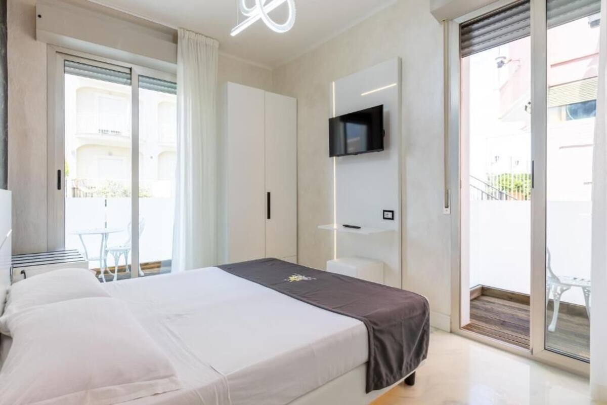 A modern bedroom with a bed, a TV mounted on the wall, and a sliding glass door leading to an outdoor area.