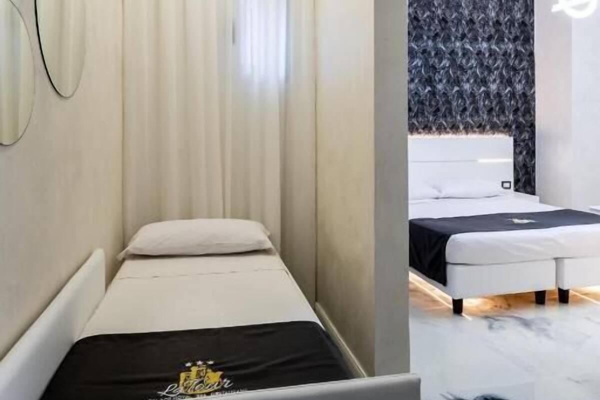 A modern hotel room with a single bed, a small seating area, and a bathroom with a shower.