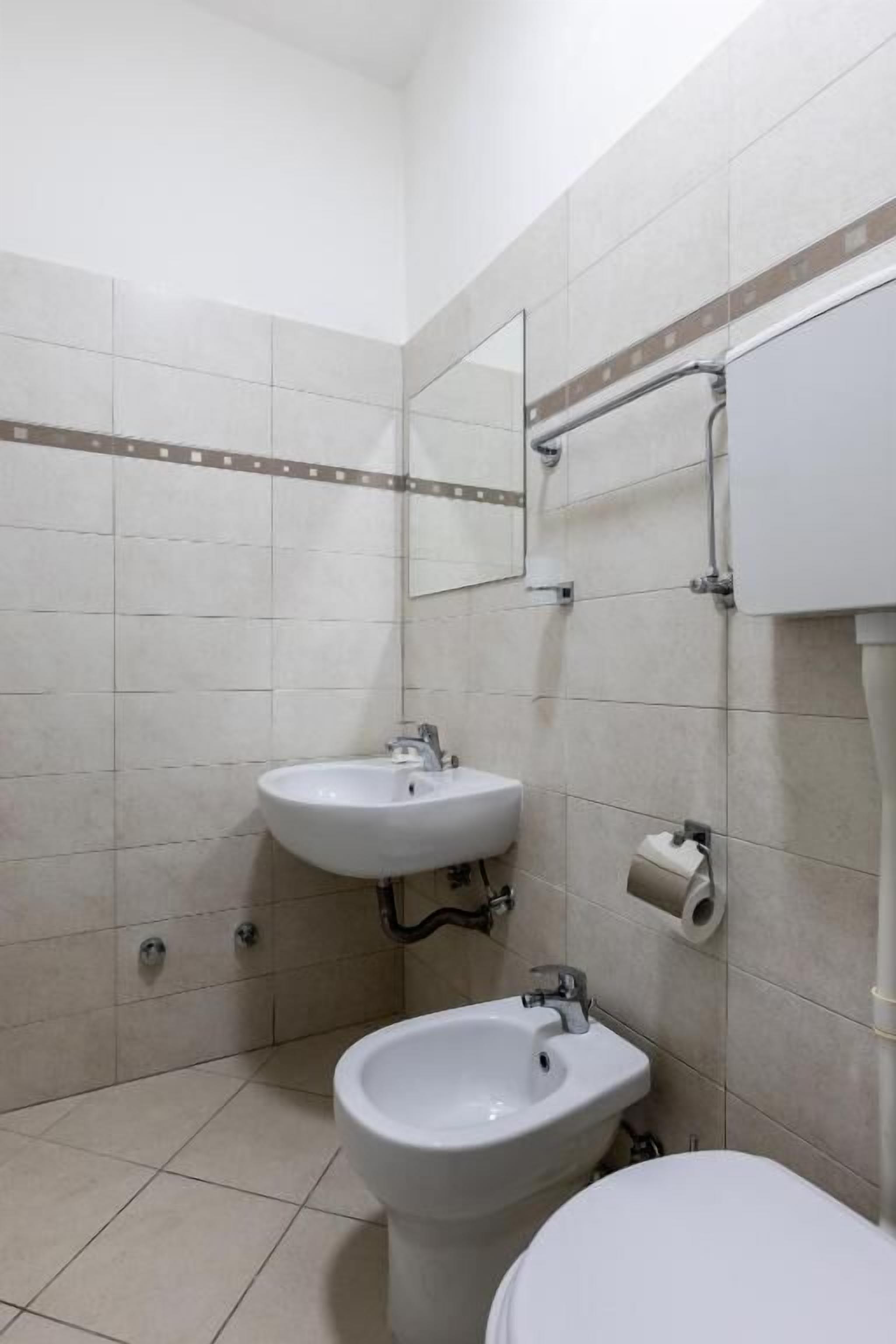 A small bathroom with a toilet, a bidet, and a sink.
