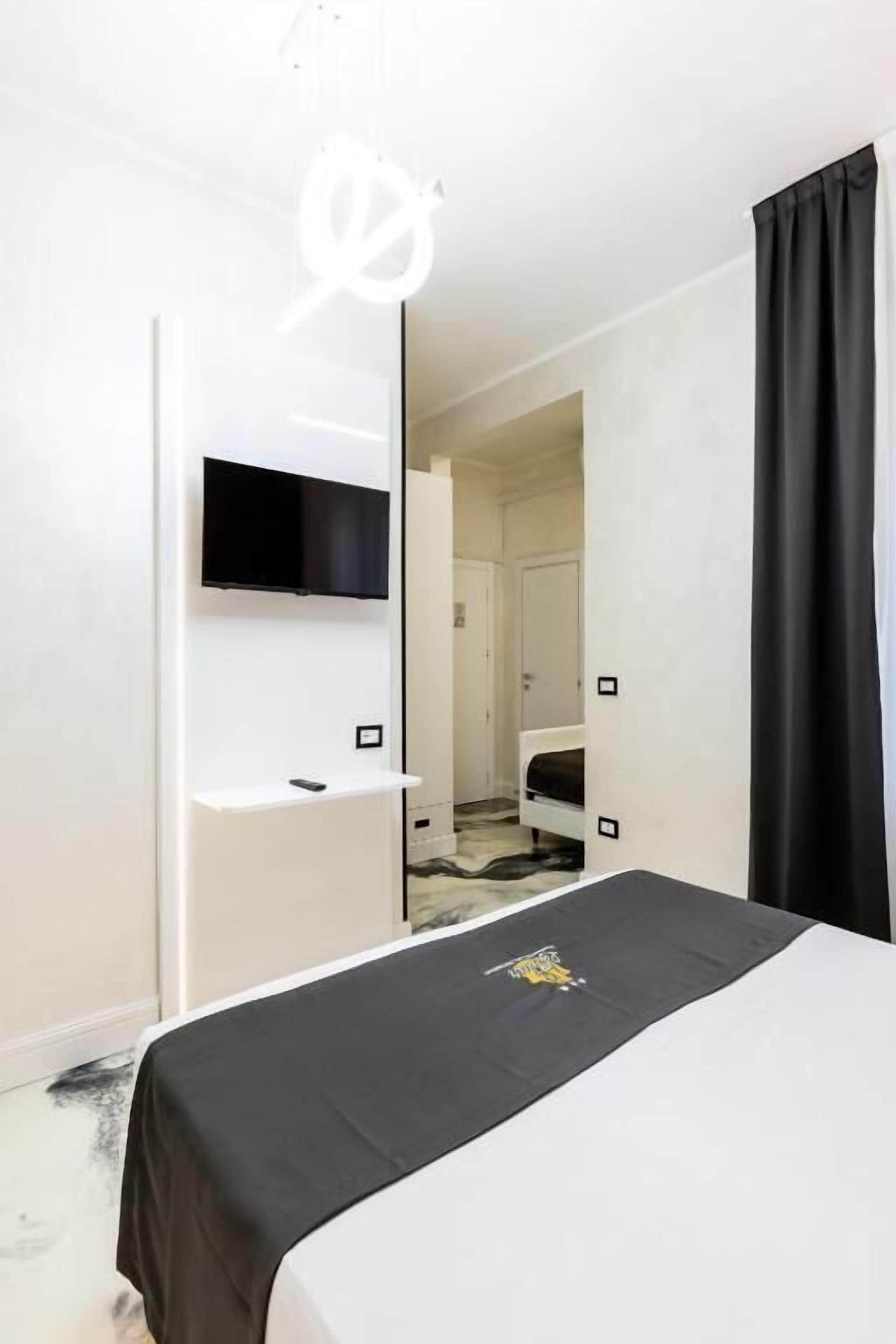 A hotel room with a bed, a mounted TV, and a door leading to another room.