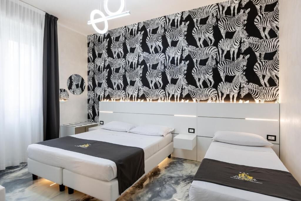 Habitación de hotel con dos camas, un cabecero estampado con diseño de cebra y suelo de mármol.