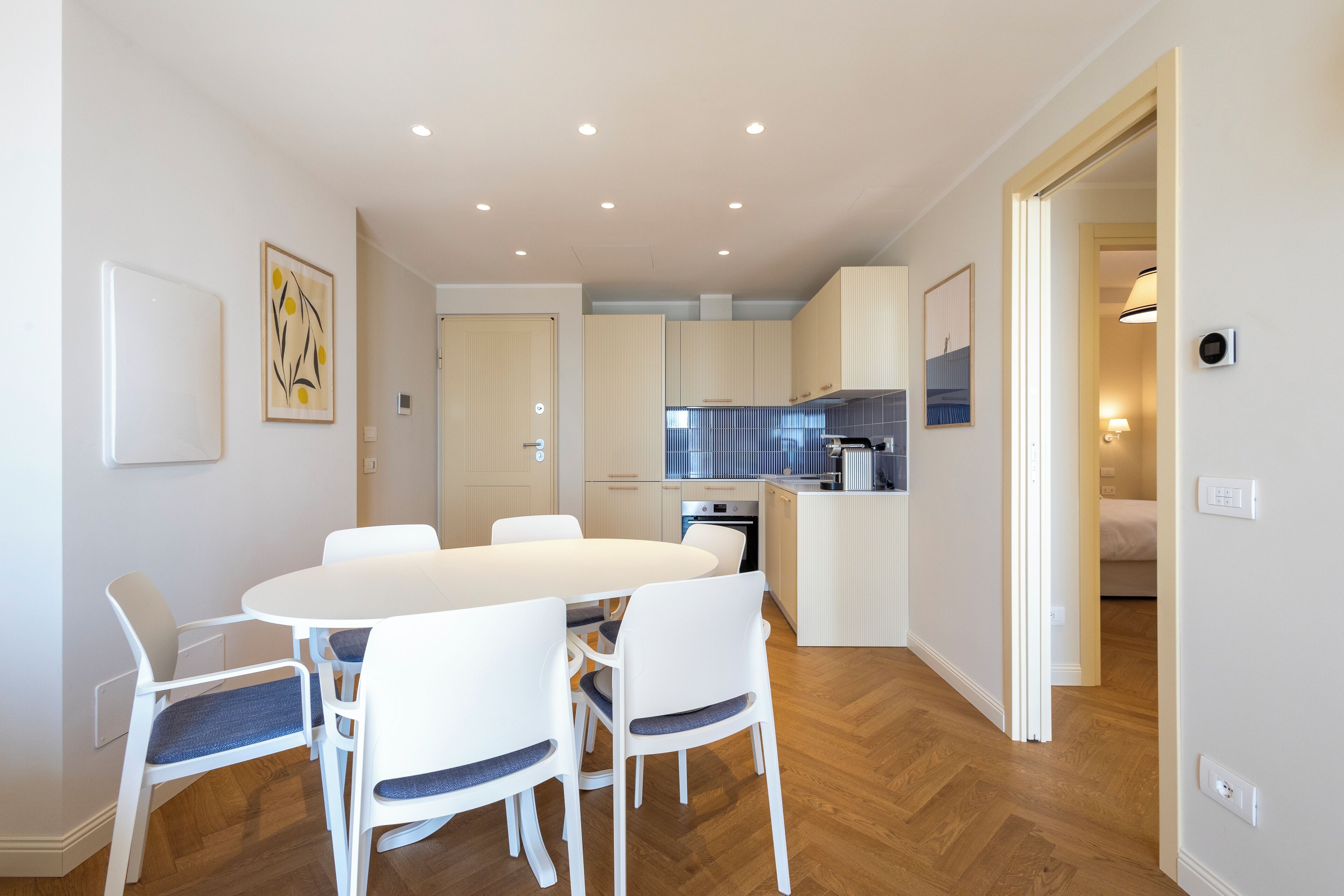 Une cuisine moderne avec des meubles blancs, un coin repas avec une table et des chaises blanches, et un plancher en bois.