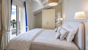 A hotel room with a bed, a wardrobe, a balcony with curtains, and a ceiling light. - A'mare Luxury Apartments (Pietra Ligure)