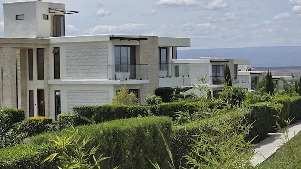 Un immeuble résidentiel moderne doté d’une façade en pierre, de grandes fenêtres et offrant une vue dégagée sur le paysage environnant.