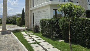 Une maison moderne à deux étages, dotée d’une façade en pierre, de grandes fenêtres et d’un balcon en verre.