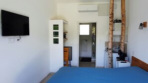 Een slaapkamer met een bed, een tv aan de muur, een kledingkast en een deur naar een badkamer.