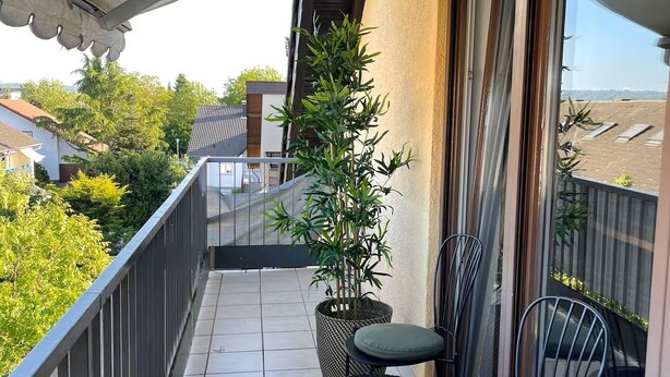 En balkon med to stole, et lille bord og en potteplante.