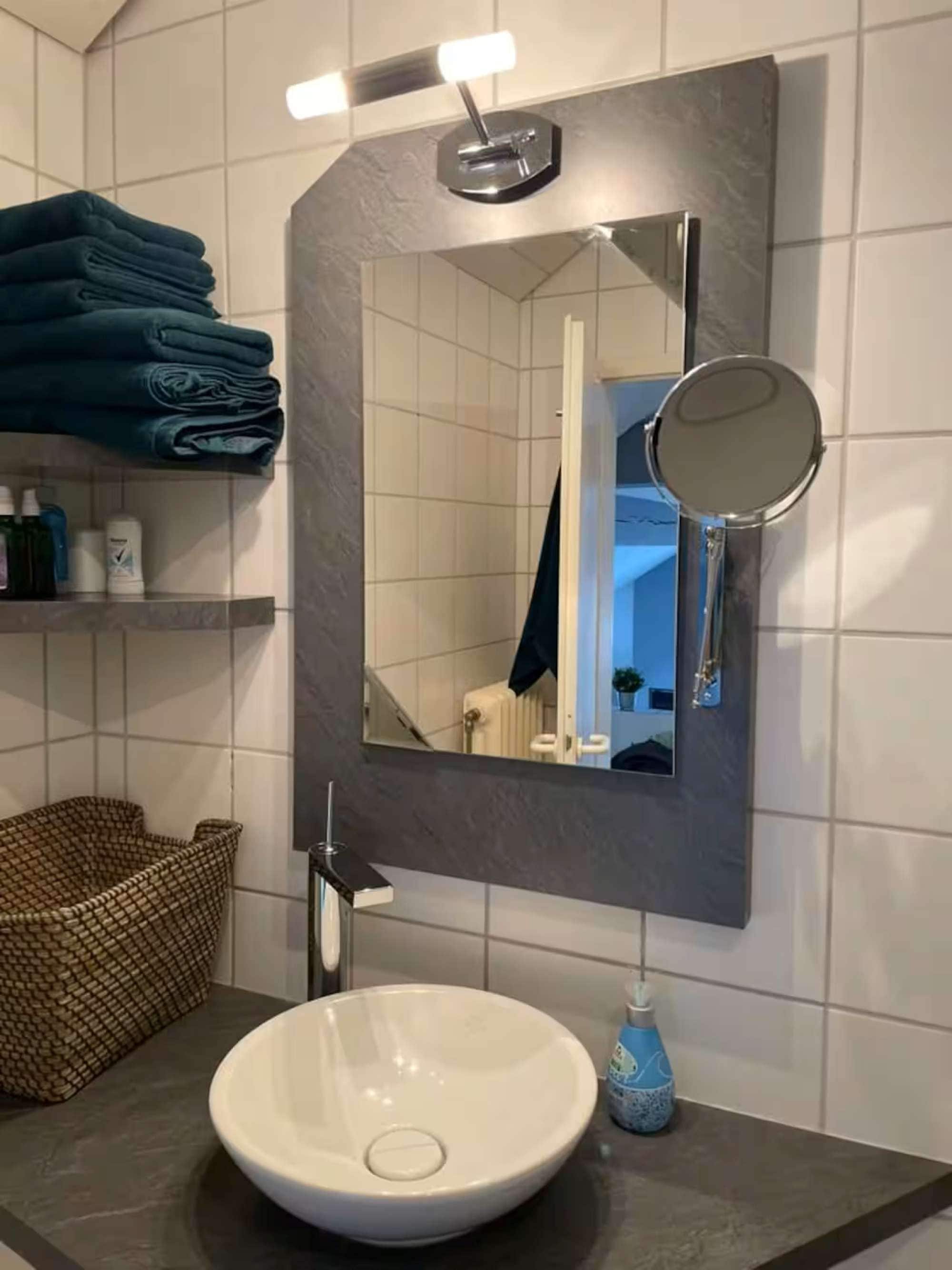 A bathroom with a white sink, a mirror, and a towel rack.