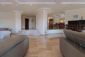 Un amplio salón con un sofá grande, una mesa de comedor y una escalera que sube a otro nivel.