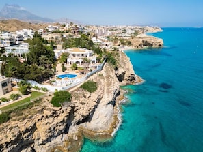A coastal resort with a pool, rocky cliffs, and buildings. - Villa Bora Montiboli by Buccara (La Vila Joiosa)