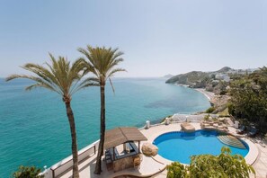 A pool with a curved edge, a palm tree, and a view of the sea. - Villa Bora Montiboli by Buccara (La Vila Joiosa)