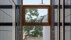 Ein modernes Badezimmer mit einem großen Fenster, einer Dusche und Blick auf einen Pool und Grünfläche.