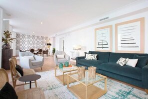 Una sala de estar moderna con un sofá verde, dos sillones, una mesa de centro y una alfombra estampada.