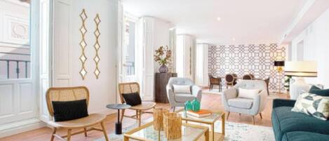 Ein stilvolles Wohnzimmer mit einem grünen Sofa, zwei Sesseln, einem Couchtisch und einem gemusterten Teppich.