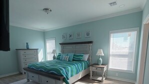 A bedroom with a bed, dresser, nightstand, and a window with blinds. - A Spacious 4 bedroom 4.5 bath Coastal Escape - Walk to the Beach (Port St. Joe)