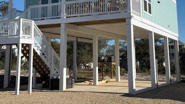 A two-story beach house with a covered deck and a staircase leading to the upper floor. - A Spacious 4 bedroom 4.5 bath Coastal Escape - Walk to the Beach (Port St. Joe)