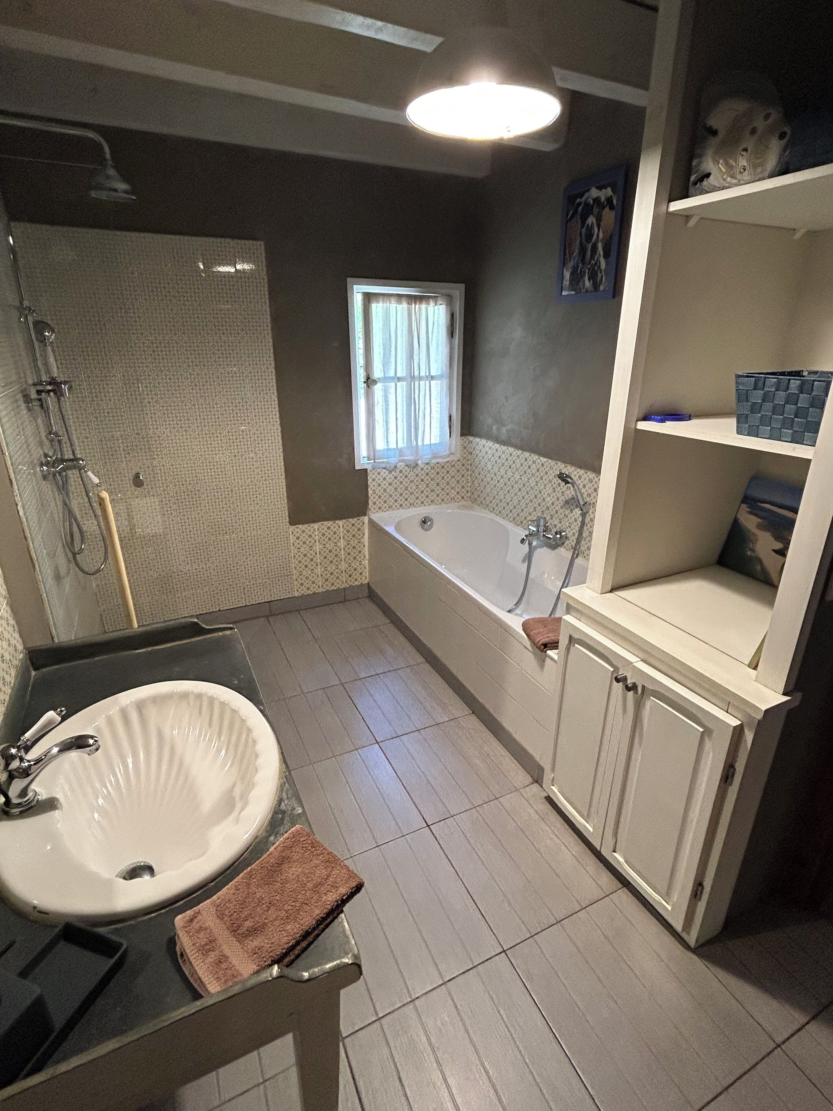 A bathroom with a bathtub, a sink, a shower, and a window.