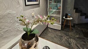 A room with a marble floor, a framed picture on the wall, a small table with a potted orchid, and a shelf with various items. - Option Hotel São Paulo - Anhembi - Expo  (São Paulo)