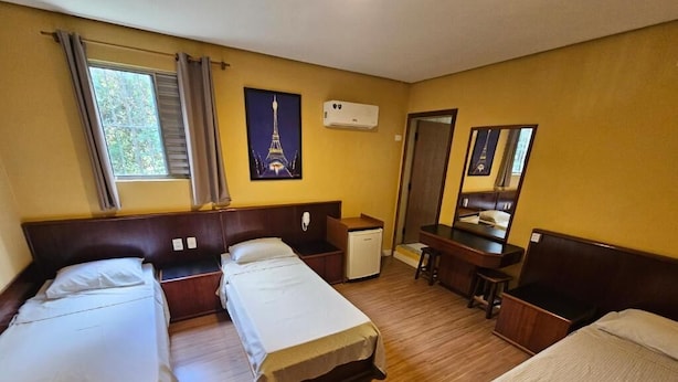 A hotel room with three single beds, a desk with a chair, a small refrigerator, and a window with curtains. - Option Hotel São Paulo - Anhembi - Expo  (São Paulo)