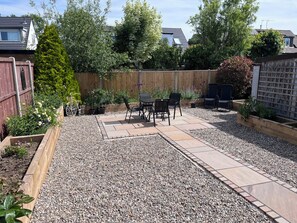A patio with a table and chairs, surrounded by a wooden fence and gravel. - Wardenlea (Preston)
