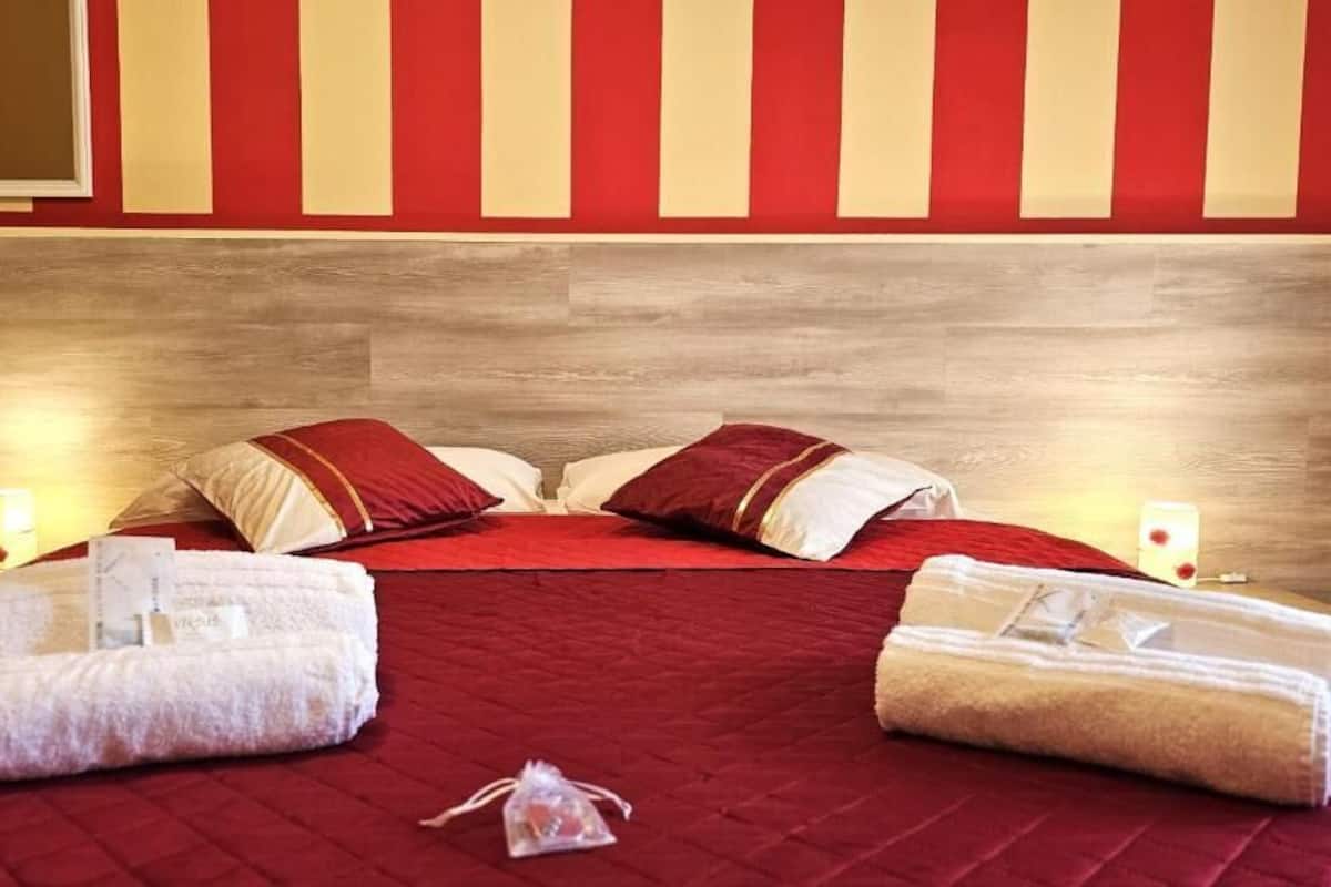 Habitació d'hotel amb un llit gran, dos coixins, dues taulletes de nit i dues tovalloles sobre el llit.