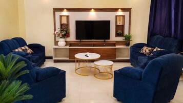 A living room with a flat-screen TV, two sofas, and two round coffee tables.