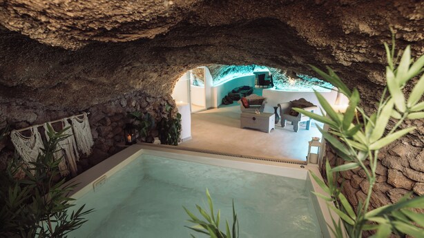 Una habitación subterránea con piscina, paredes de piedra y un espacio para sentarse.