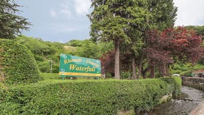 A sign for Rhaeadr Dyserth Waterfall with amenities listed: cafe, toilets, and car park. - Bronafon (Rhyl)