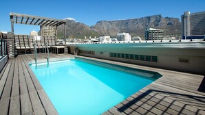 A rooftop pool with a wooden deck, a pergola, and a cityscape with mountains in the background. - Greenmarket Place 503 (Cape Town)