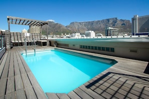 A rooftop pool with a wooden deck, a pergola, and a cityscape with mountains in the background. - Greenmarket Place 503 (Cape Town)