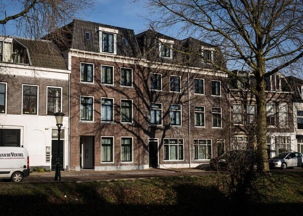 Un immeuble résidentiel à plusieurs étages, doté d’une façade en briques, de nombreuses fenêtres et d’un arbre devant.
