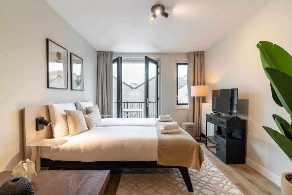 Ein Hotelzimmer mit Bett, Fernseher, Schreibtisch und einem Balkon mit Aussicht.