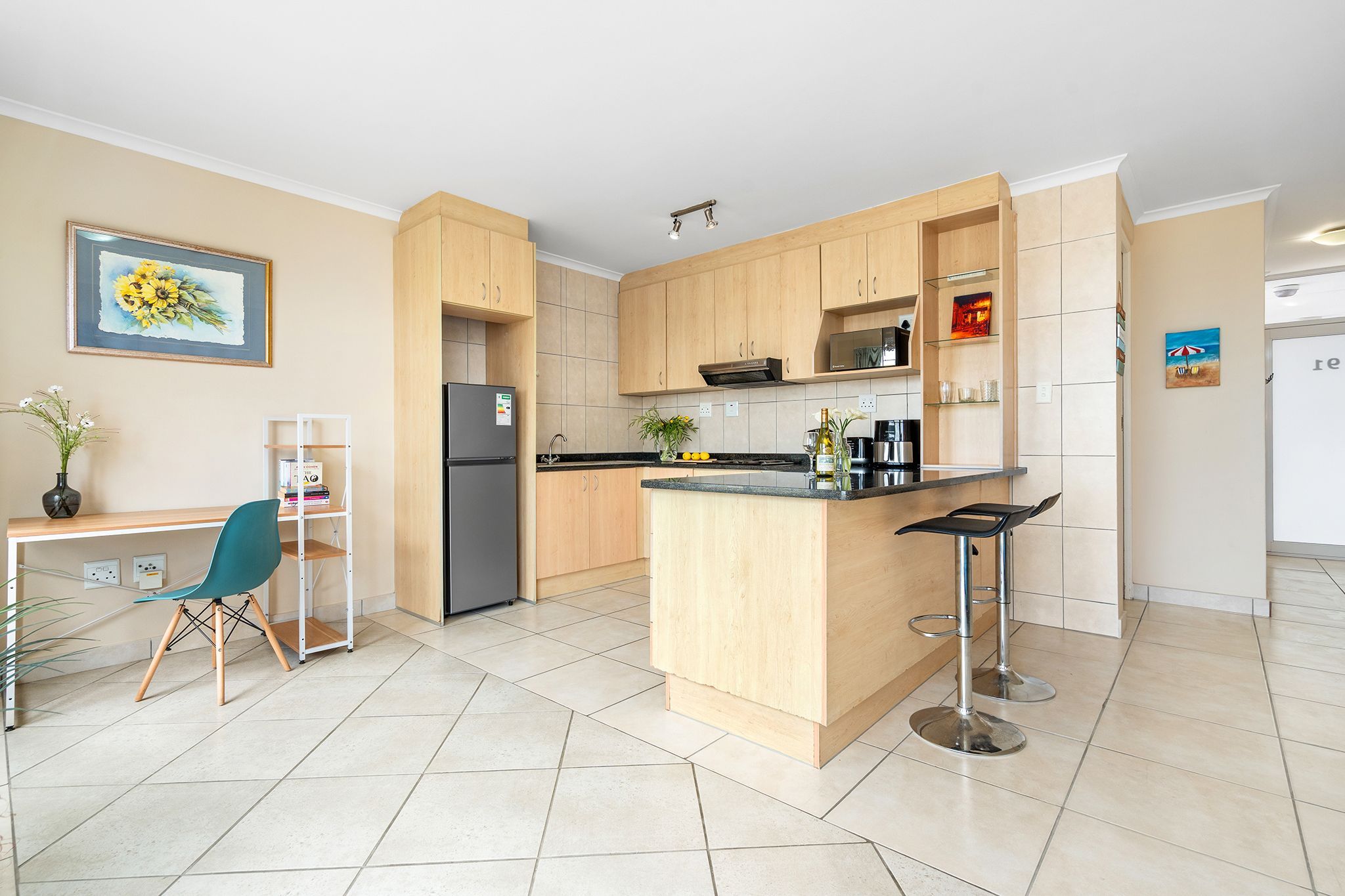 Een moderne keuken met houten kasten, een centraal eiland en een barkruk.