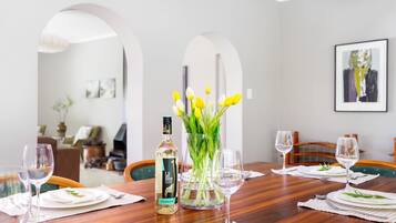 Una mesa de comedor servida con platos, vasos y una botella de licor.