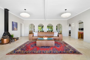 A spacious living room with a brown leather sofa, a patterned rug, and a large fireplace. - Riebeek-kasteel Villa (Riebeek Kasteel)