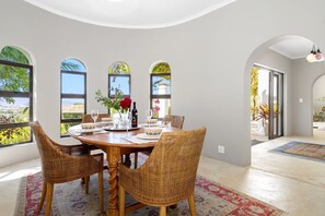A dining area with a round table, wicker chairs, and a view through large windows. - Riebeek-kasteel Villa (Riebeek Kasteel)
