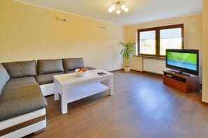 Ein Wohnzimmer mit einer Couch, einem Couchtisch, einem Fernseher und einer Zimmerpflanze.