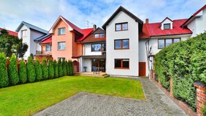 Une rangée de maisons modernes aux toits rouges, avec une allée pavée et une pelouse bien entretenue.