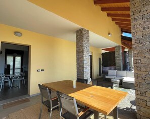 A modern interior with a wooden dining table, metal chairs, a stone pillar, and a stone wall. - Apartment La Terrazza (Cannero Riviera)