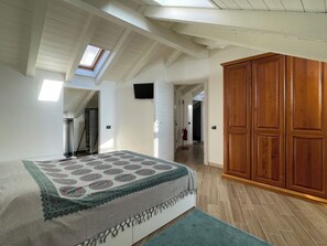 A bedroom with a bed, a wooden wardrobe, a skylight, and a hallway. - Apartment La Terrazza (Cannero Riviera)