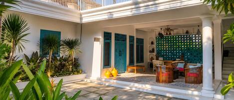 A courtyard with a covered seating area, white columns, and a balcony.