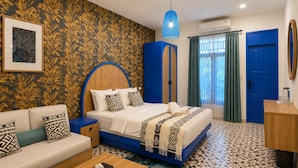 A bedroom with a bed, a sofa, a coffee table, a wardrobe, a desk, and a window with curtains.