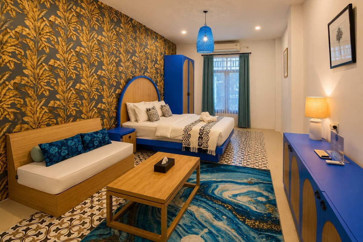A hotel room with a bed, a sofa, a coffee table, and a desk.