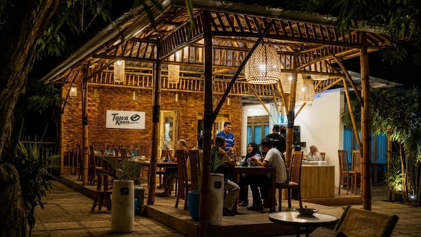 A restaurant with a brick exterior, wooden pergola, and outdoor seating.