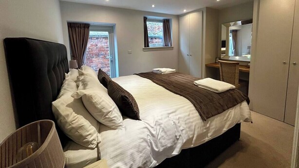 A bedroom with a large bed, a desk, a chair, and a wardrobe. - Boutique Barn Secure Parking between York &Harrogate (York, North Yorkshire)