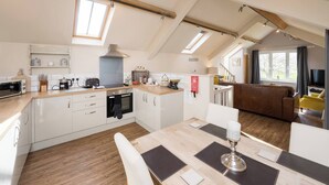 A modern kitchen with a central island, built-in oven, and a dining area with a table and chairs. - Boutique Barn Secure Parking between York &Harrogate (York, North Yorkshire)
